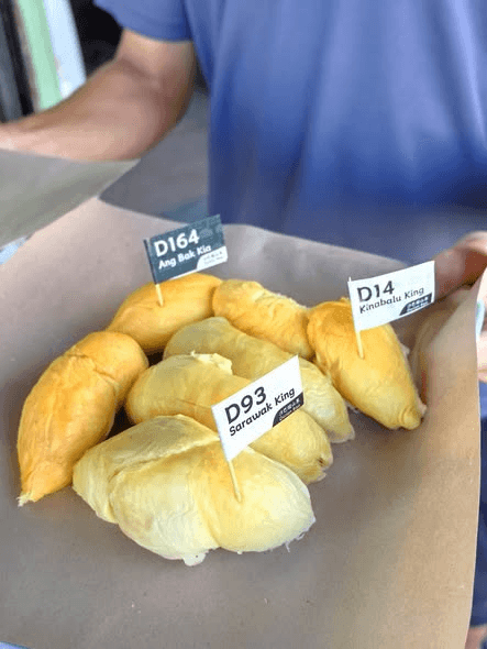 A tray of durian pieces marked with variety labels.